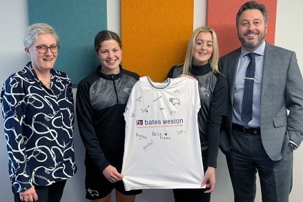 Olivia and Grace with Kay Brookes and Wayne Thomas presenting a signed shirt to their squad sponsors, bates Weston